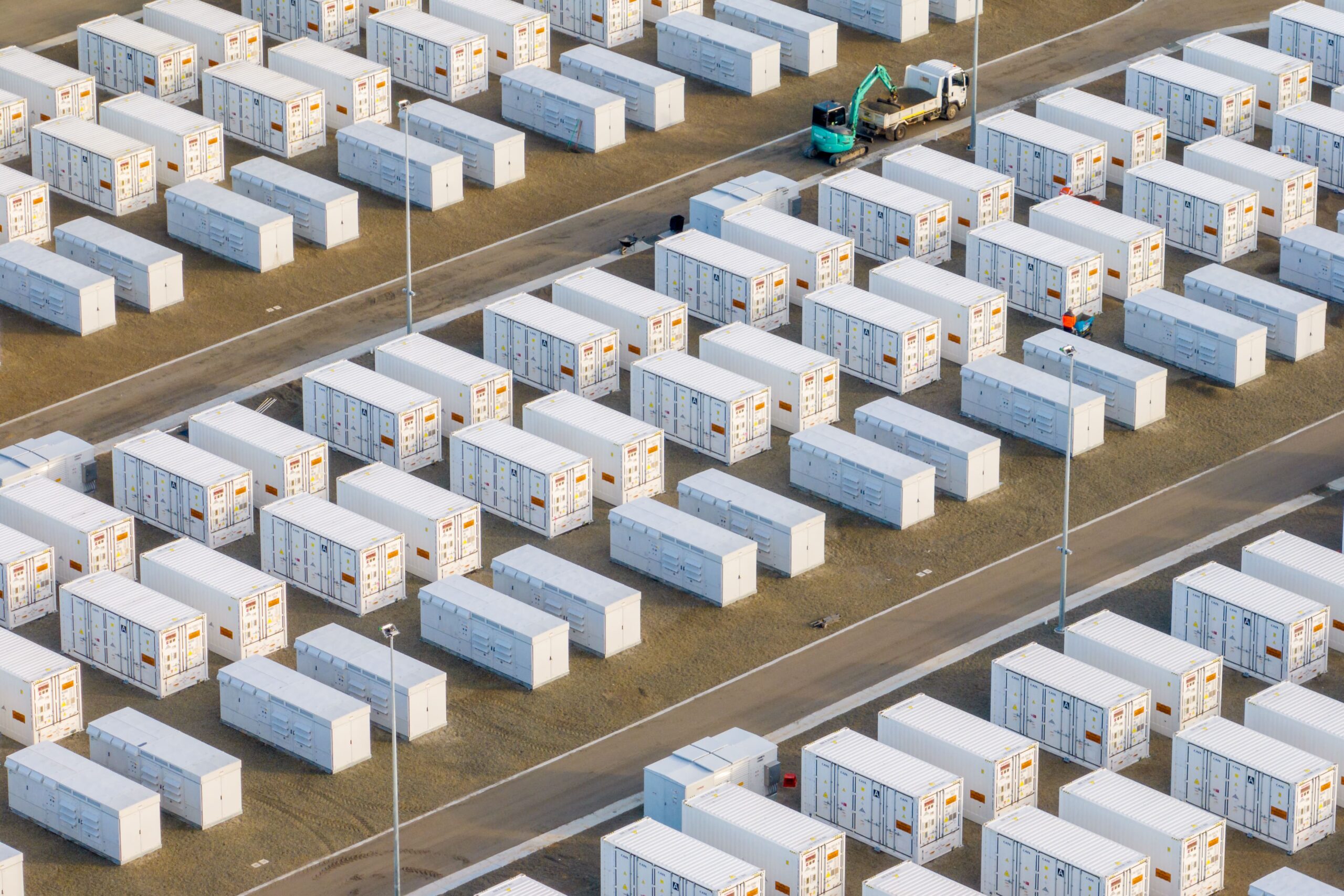 Rows of white energy storage containers with crane nearby.